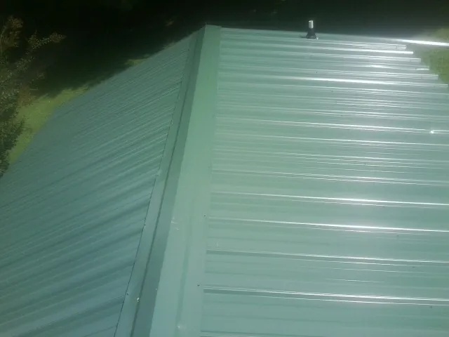 New green metal panels meeting at the ridge of a roof — Flat Roof Repair work by our crew in Plato