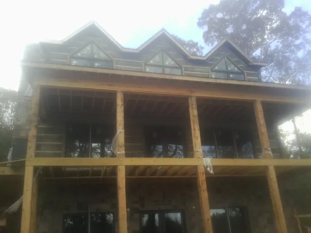Dormers and porch framing on a large log home under construction — Roof Coating work by our crew in Plato