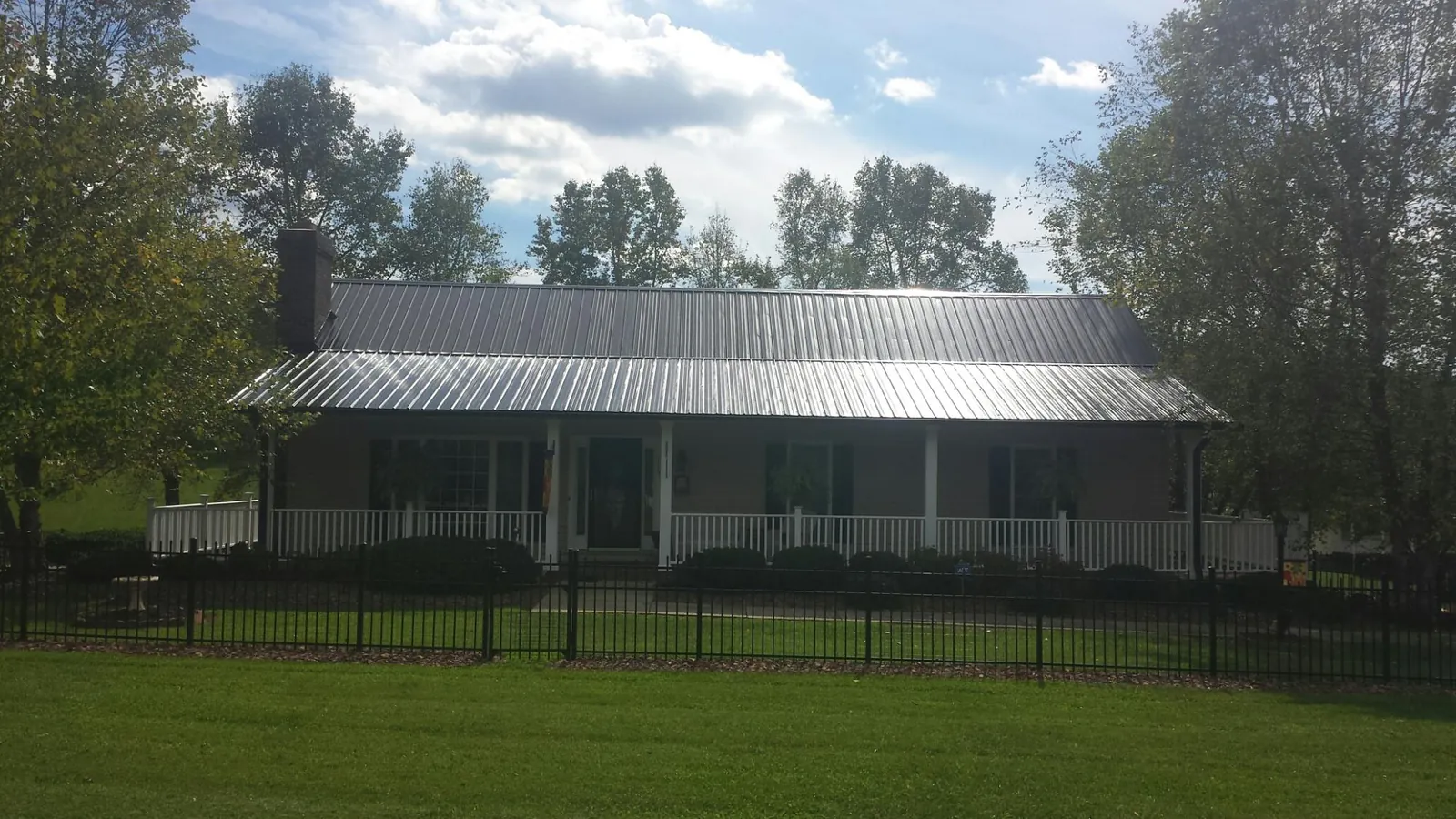 Gray metal roof on a brick ranch with a full width front porch — Gutter Guard Installation work by our crew in Plato
