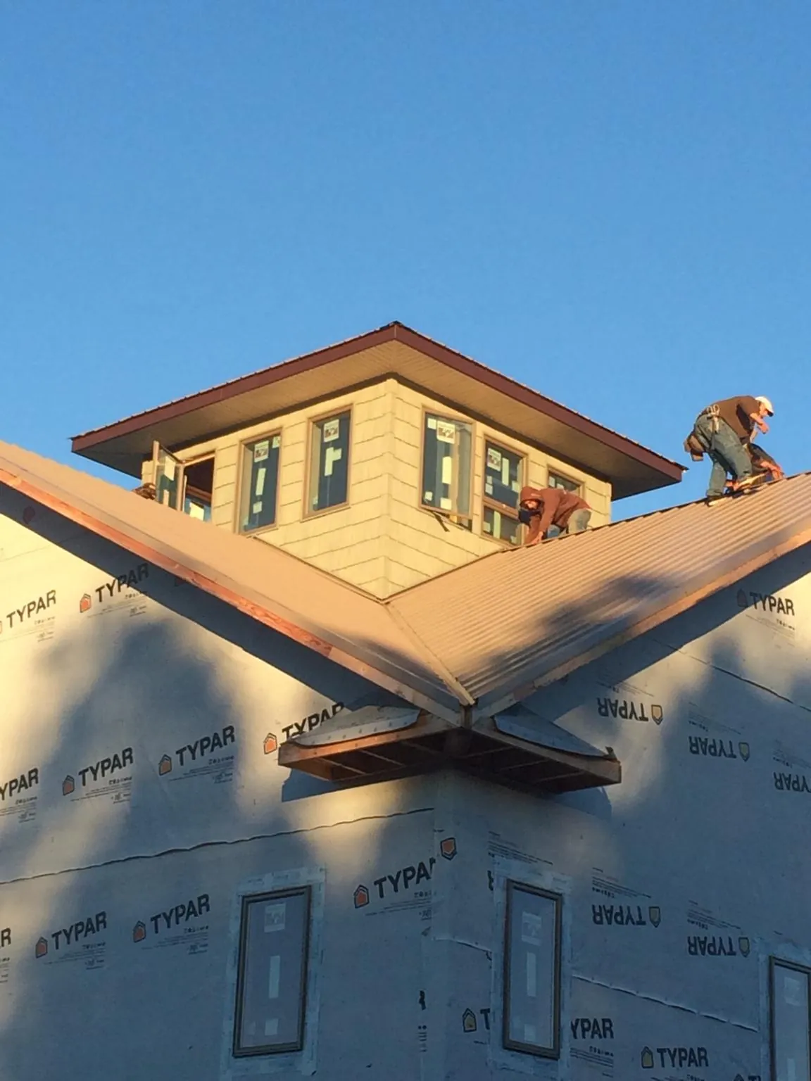 Roofers working around a rooftop cupola on a new metal roof at sunset — Roof Waterproofing in Plato by Roofing Brothers